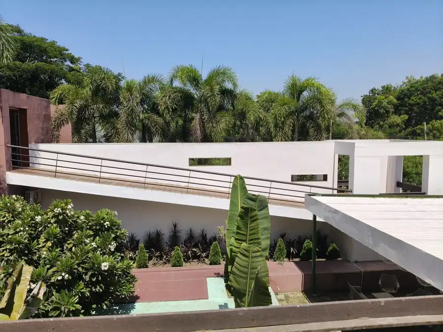 Planted terraces below a white house, with palms, agaves and low hedges holding the slope