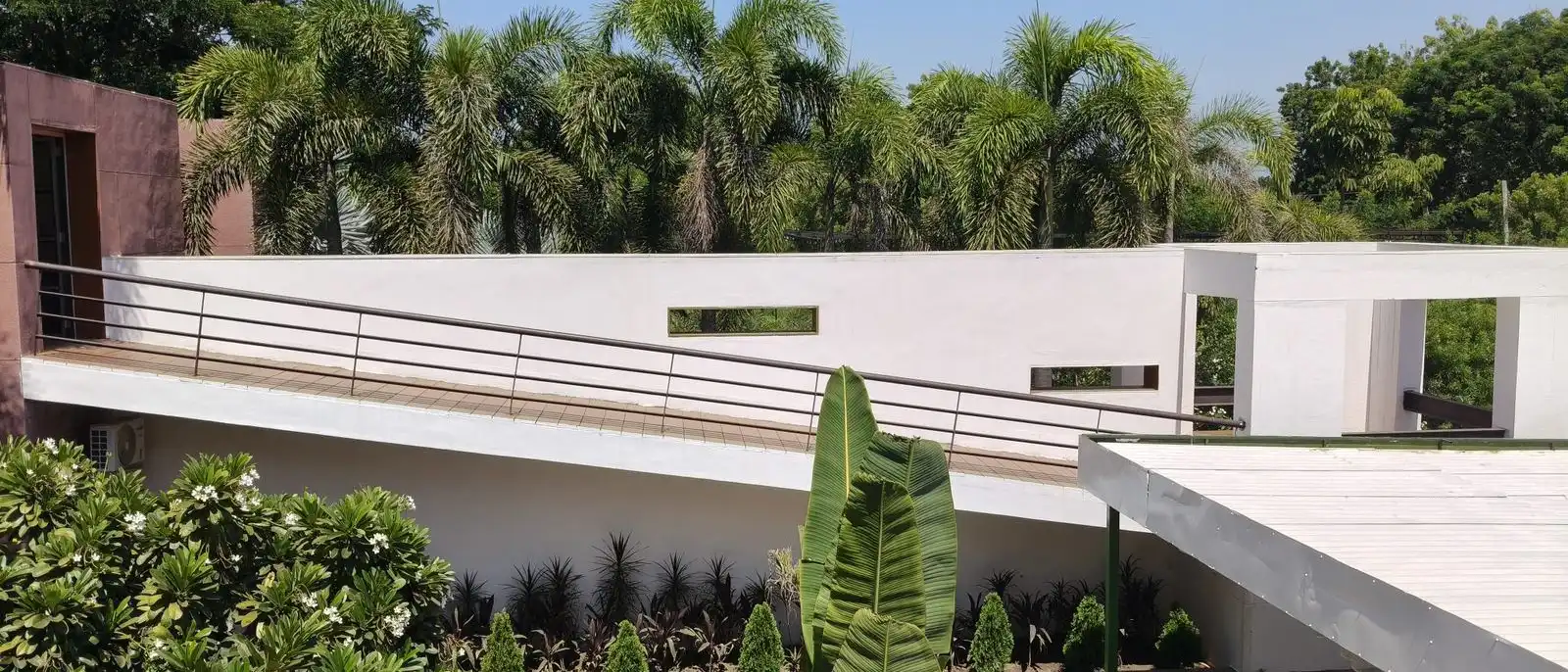 Planted terraces below a white house, with palms, agaves and low hedges holding the slope